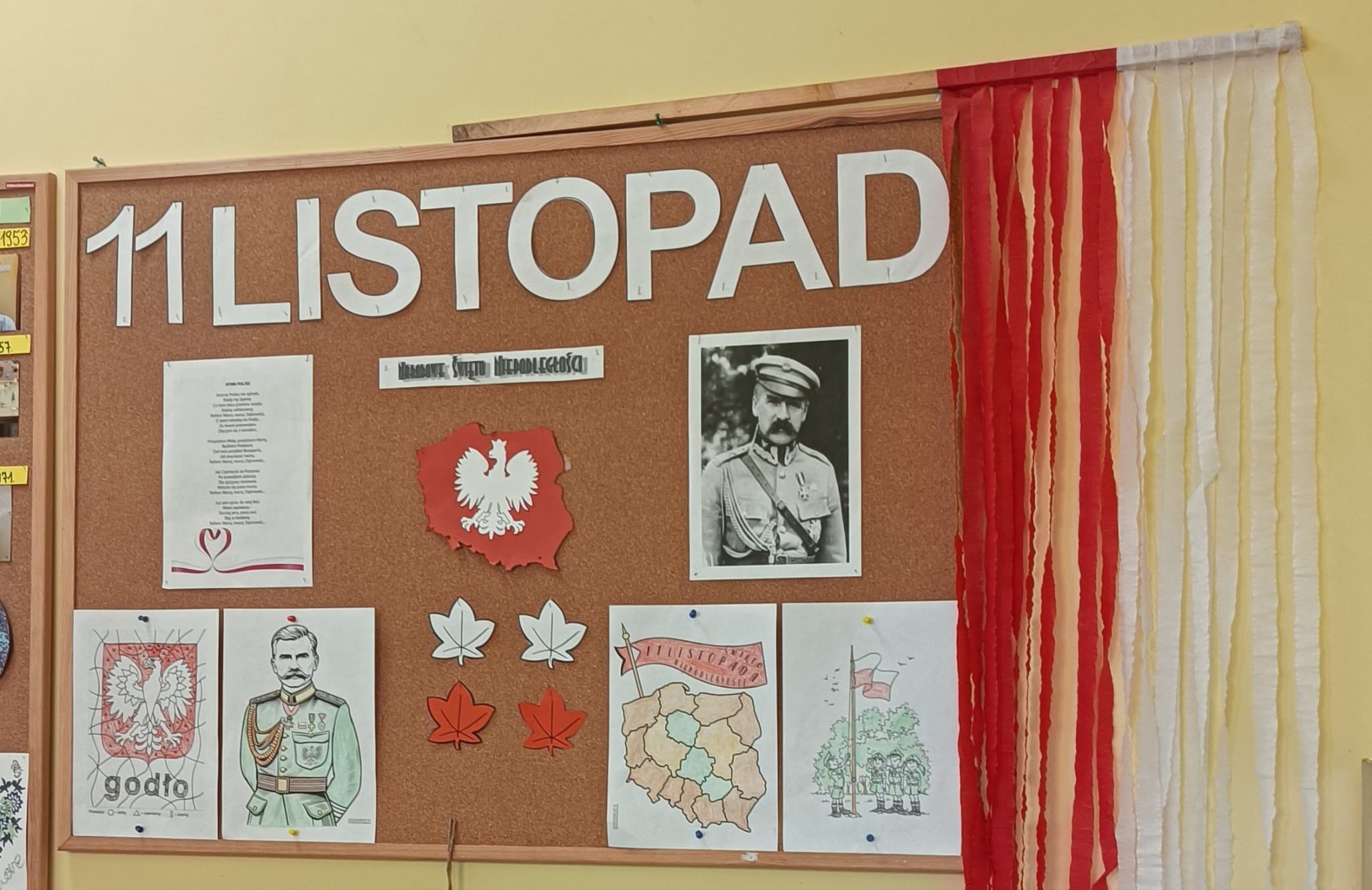 tablica z powieszonymi symbolami patriotycznymi Polski flaga godło rysunki piłsudski 