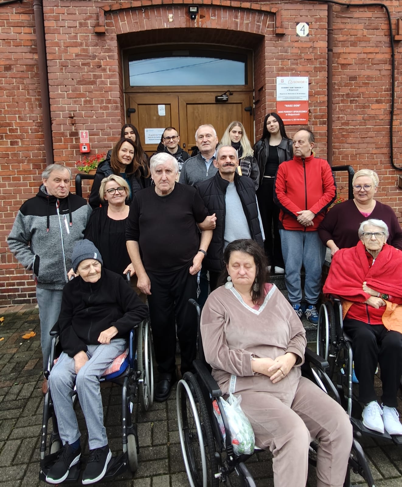 Ludzie w tym mieszkańcy DPS i goście przed wejściem główny DPSu 