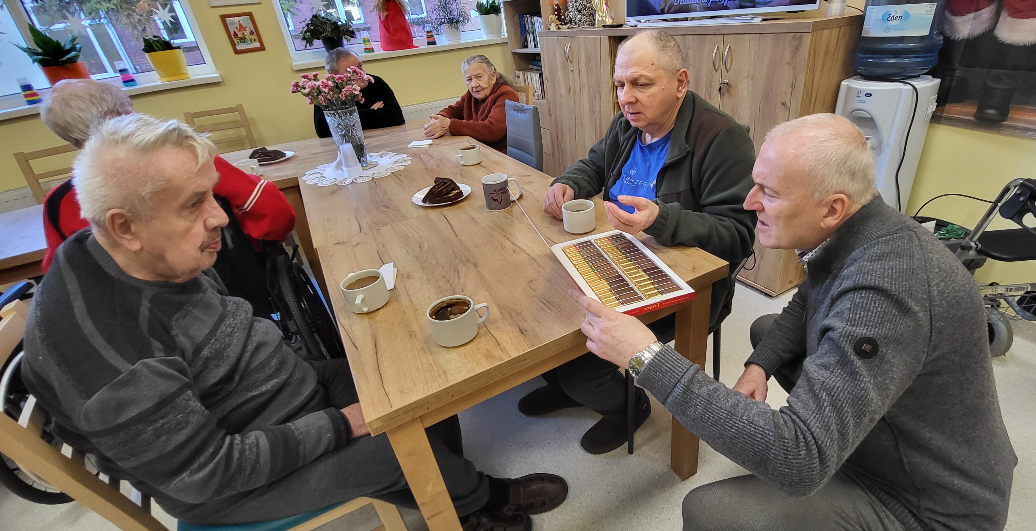 Dyrektor DPS Maciej Nejman częstujący mieszkańców DPS czekoladkami