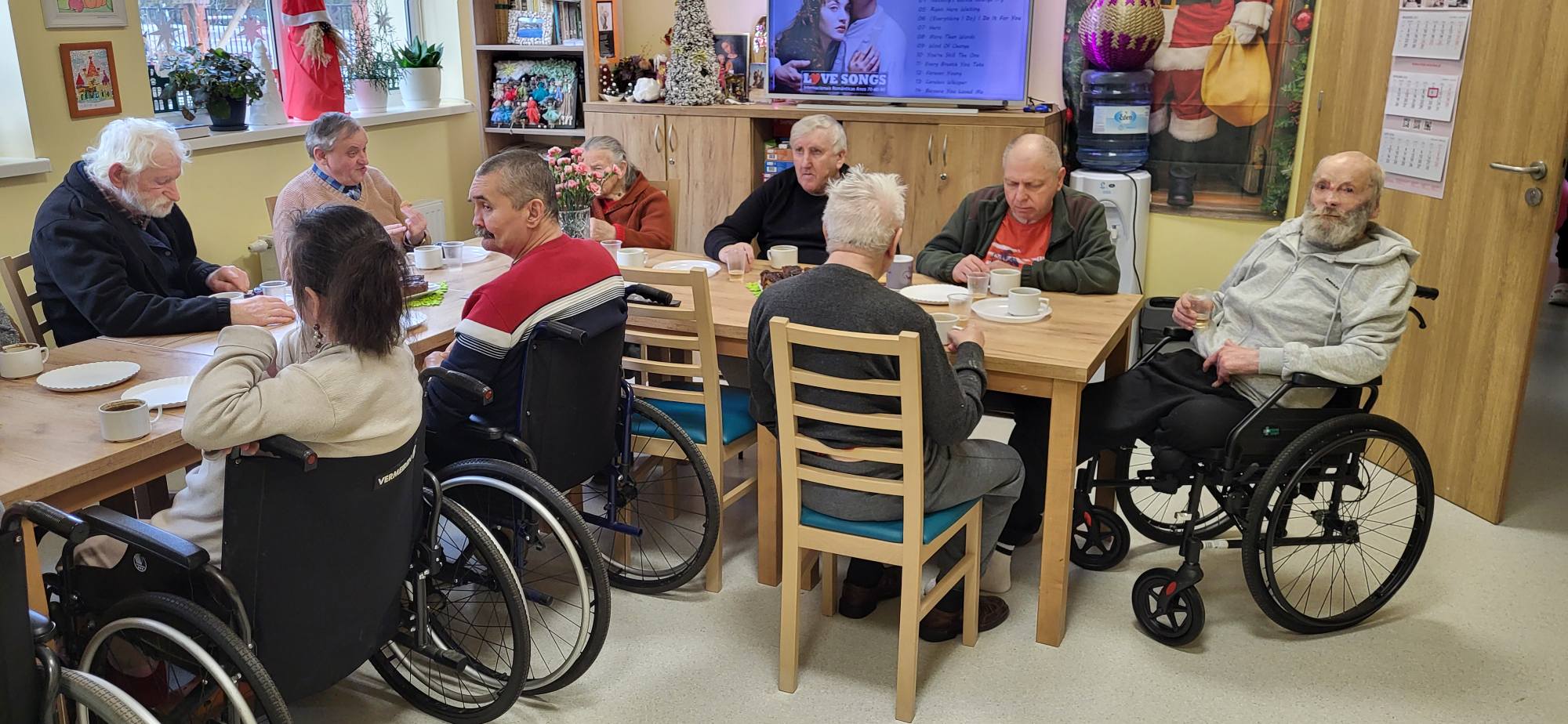 Mieszkańcy DPSu przy stole rozmawiają pijąc kawę 