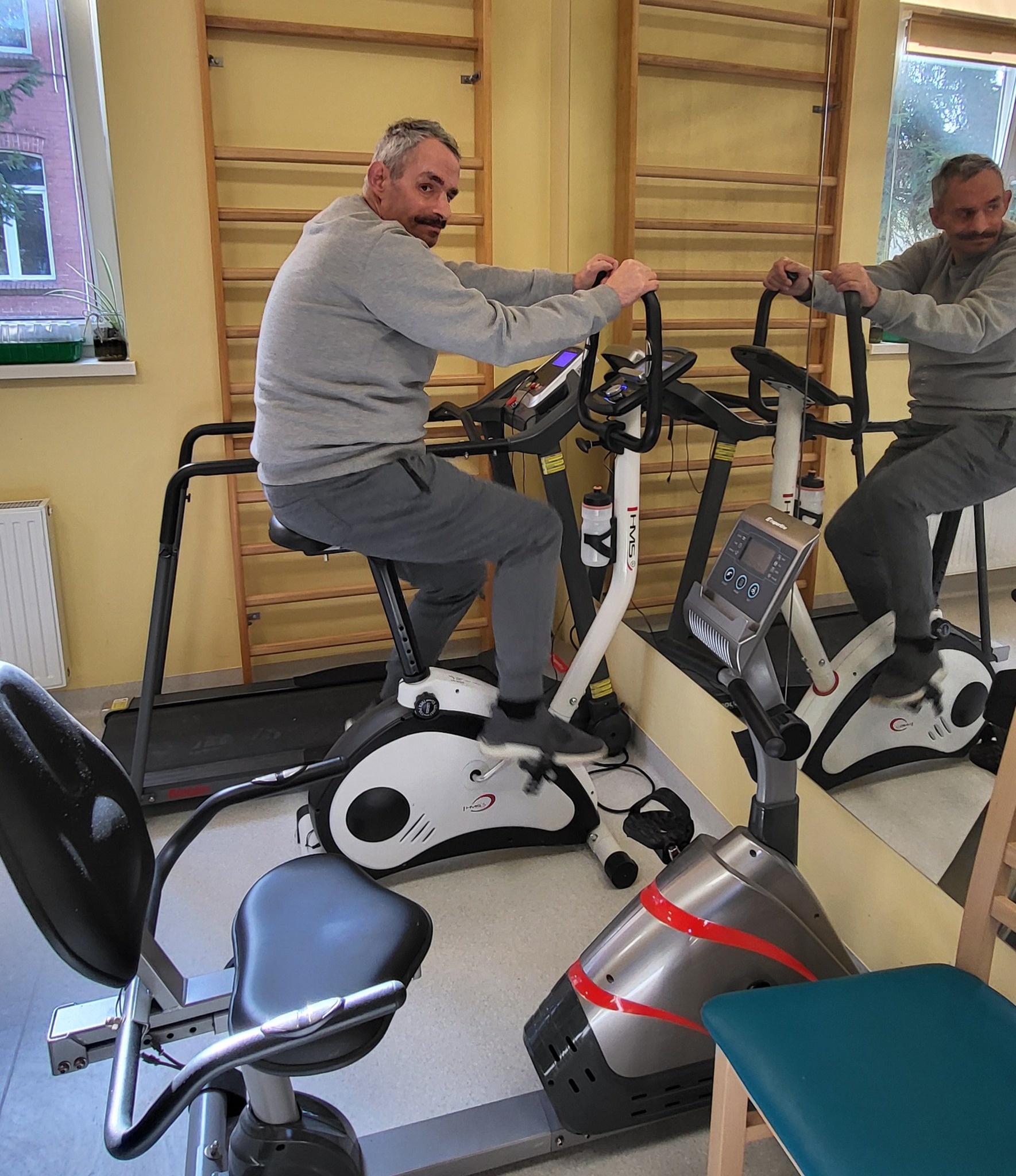 Mieszkaniec DPS ćwiczy na rowerku 